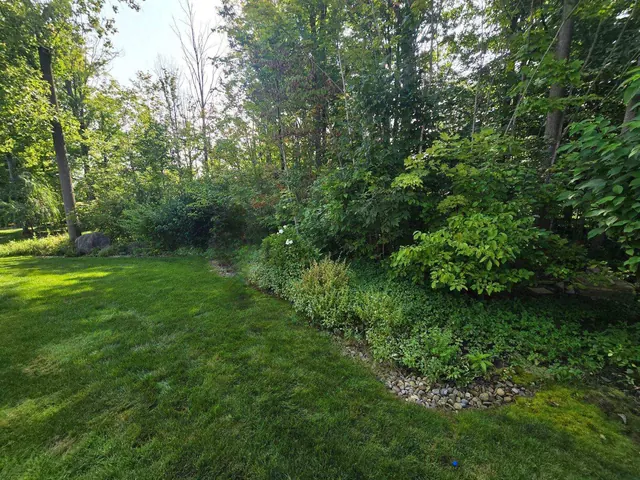 Crisp lawn edge along a wooded bed bordered with river rock